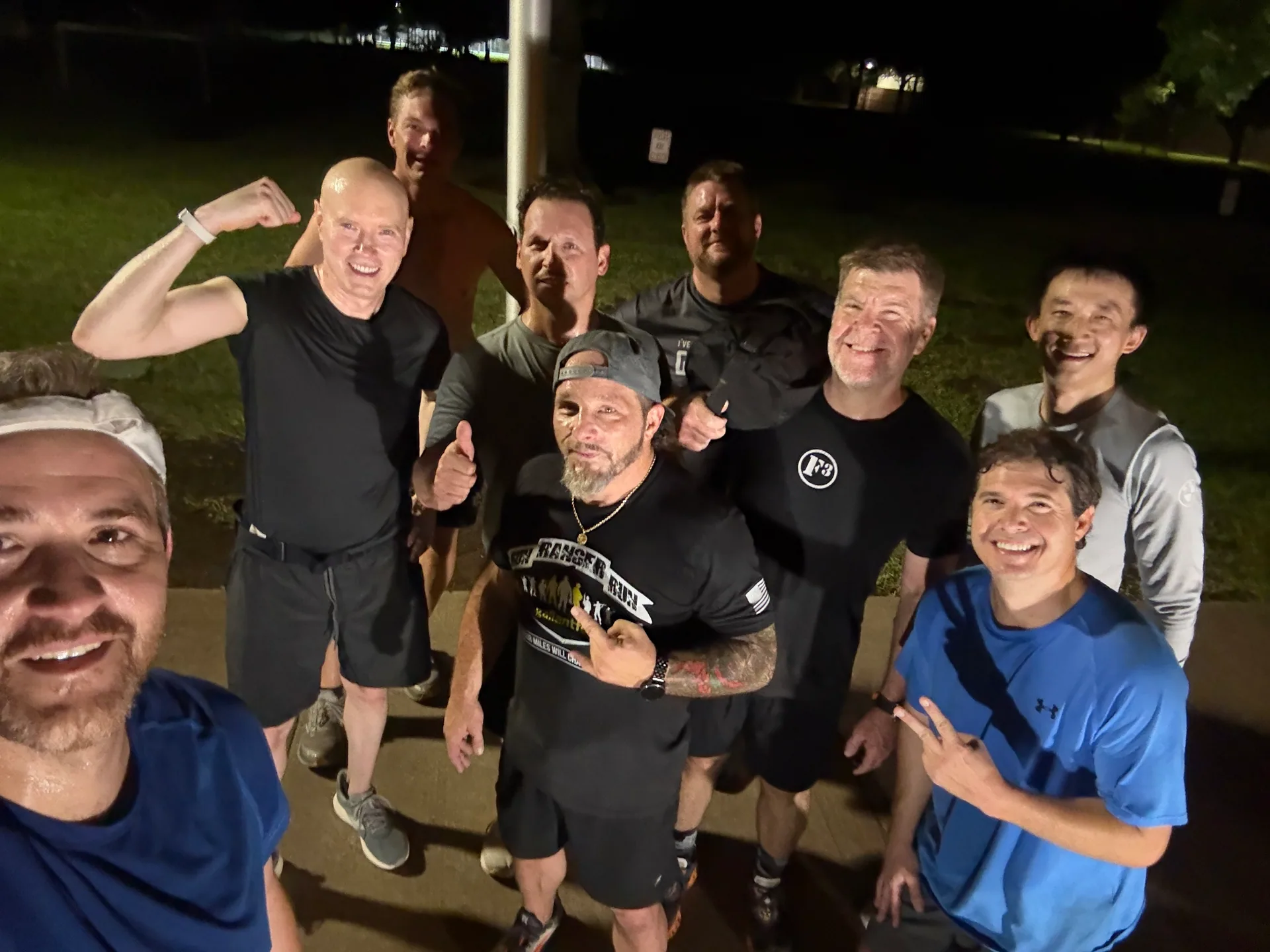 F3 Dallas members smiling together beside a flagpole at night