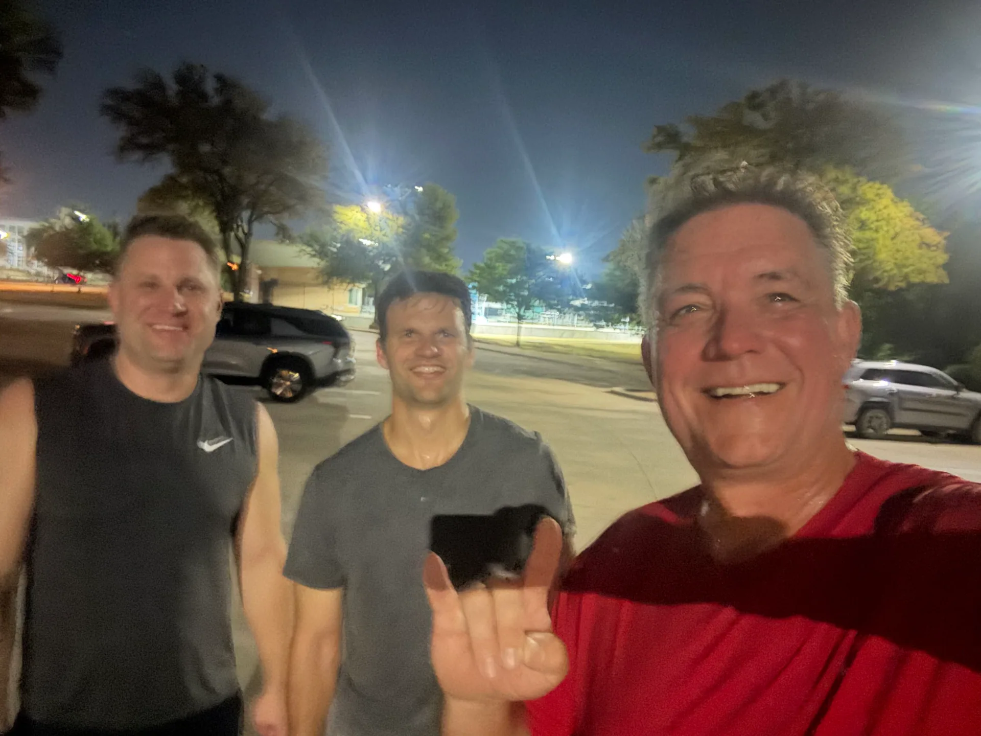 Three F3 Dallas members taking a selfie in a parking lot at night